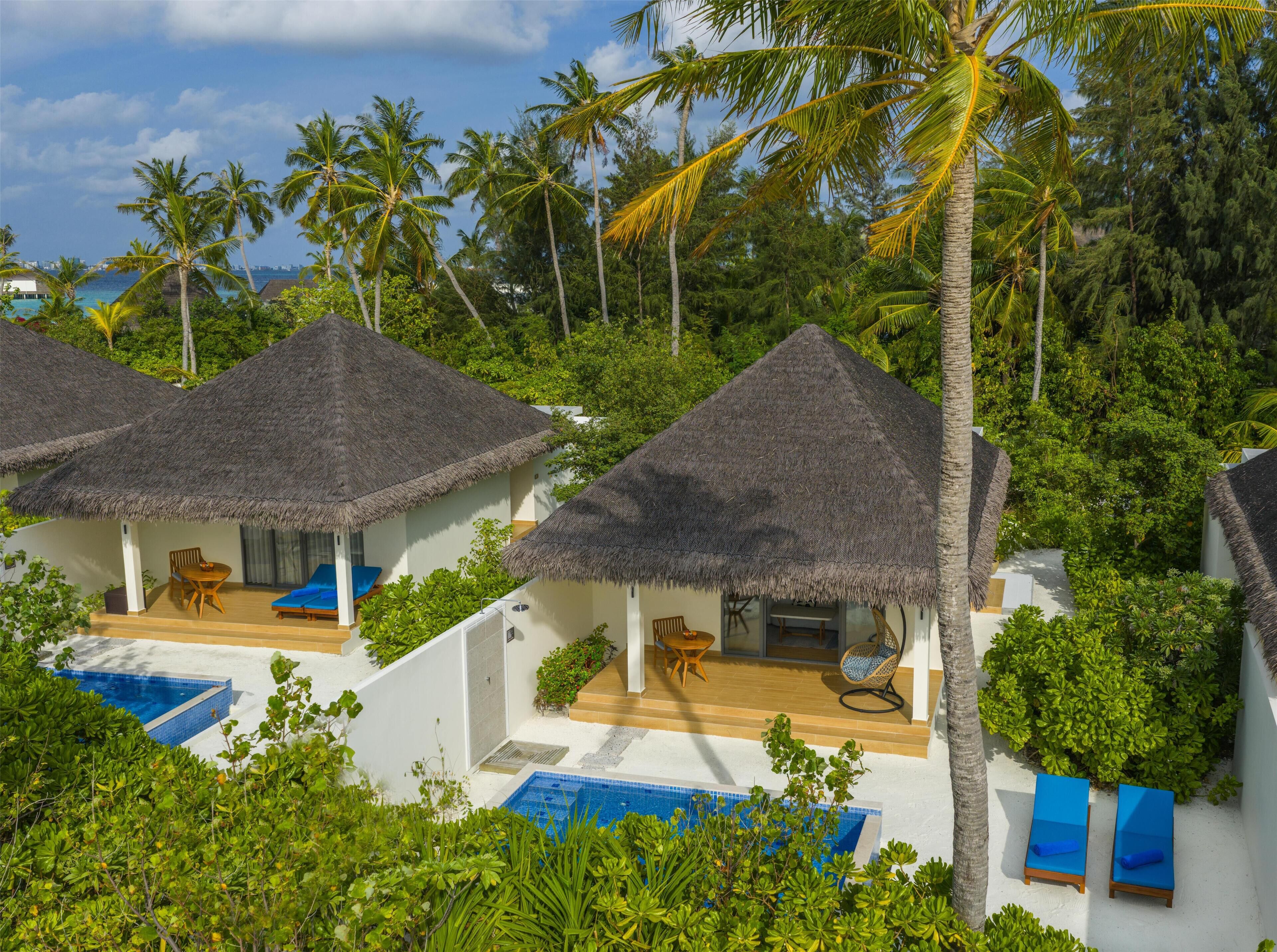 Un resort con villas de techo de paja, piscinas privadas y exuberantes alrededores tropicales.