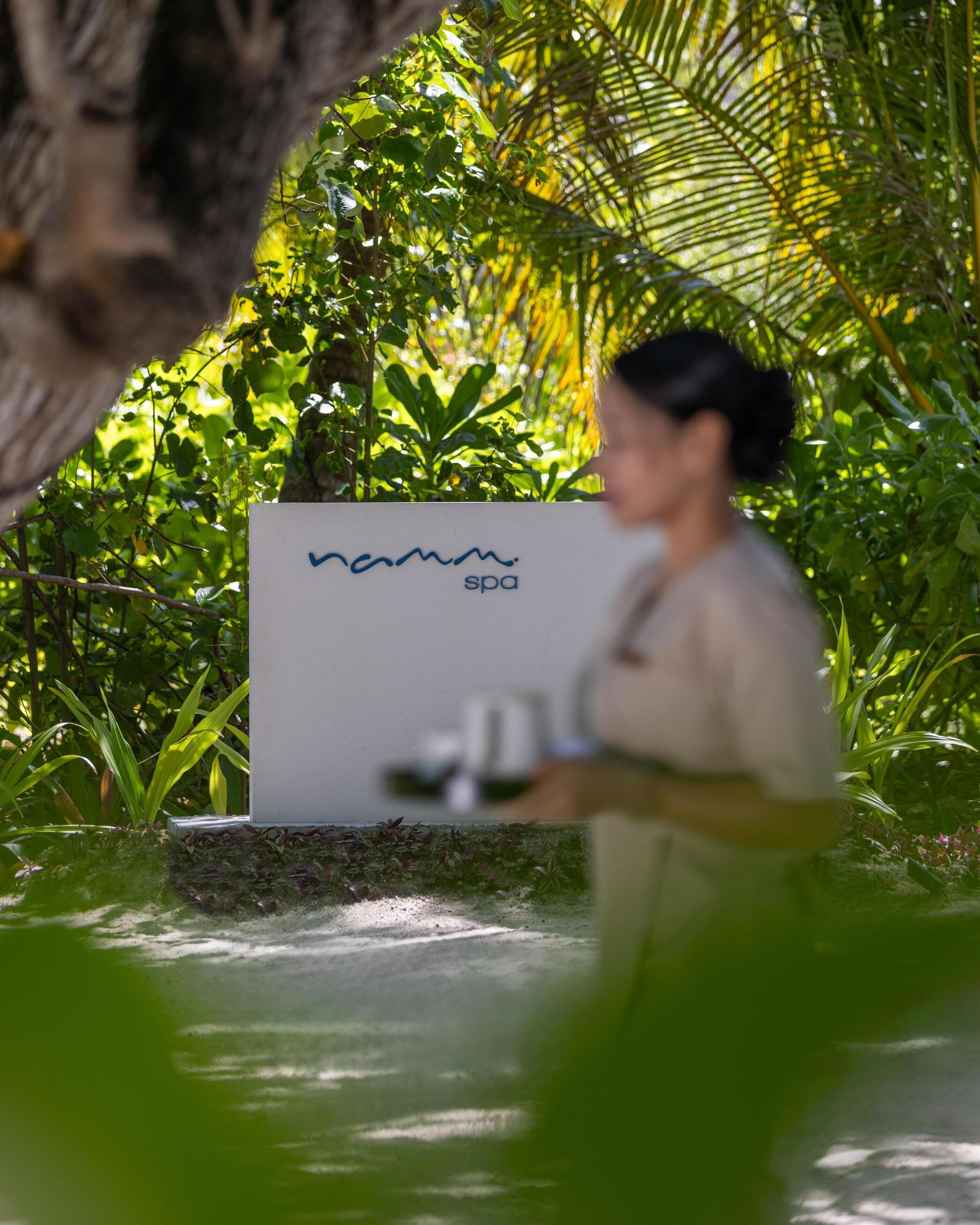 Une enseigne indiquant un spa, portant le nom « namann spa », au milieu d’une végétation luxuriante.