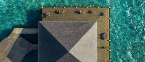 An aerial view of a resort with a large central building, multiple smaller structures, and clear turquoise waters.