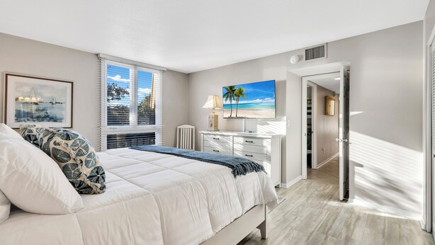 A bedroom with a bed, a desk, a chair, a painting, and a window. - 889 Ketch Court @ Harbour Town, Sea Pines | Pool Access | Walk to Marina & Golf Links (Hilton Head Island)