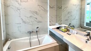 Une salle de bain moderne avec une baignoire sur pieds, un grand miroir et des carreaux de marbre.