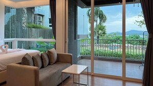 Une chambre d’hôtel moderne dotée d’un balcon, d’un canapé, d’une petite table et d’un lit agrémenté d’une décoration en forme de cœur.