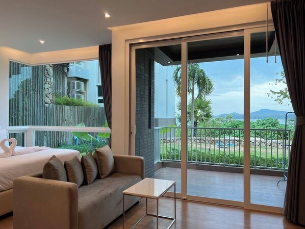 Una habitación de hotel moderna con balcón, un sofá, una mesita y una cama decorada con forma de corazón.