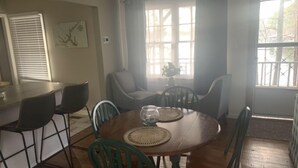 A dining area with a wooden table, green chairs, and a bar counter.