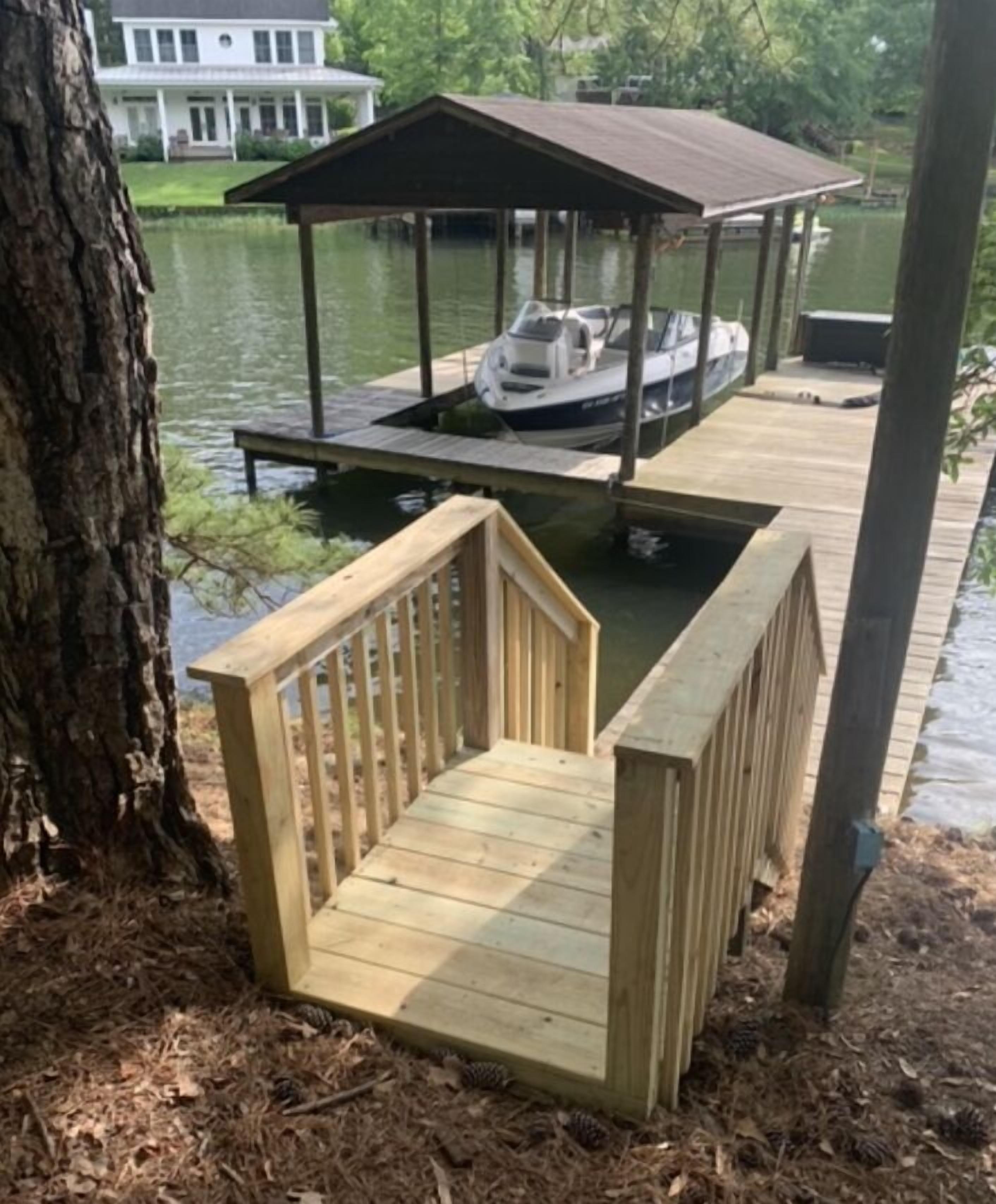 A wooden dock with a small wooden structure on it, a tree, and a body of water in the background.