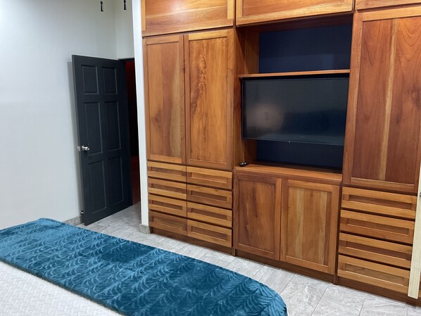 Un dormitorio con cama, armario de madera y televisor.