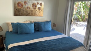 A bedroom with a bed, pillows, a painting, and a view through a door. - Lovely 2 bedroom home with large Private salt water pool in beautiful Tamarindo. (Tamarindo)