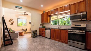 A modern kitchen with wooden cabinets, stainless steel appliances, and a large window. - Lovely 2 bedroom home with large Private salt water pool in beautiful Tamarindo. (Tamarindo)