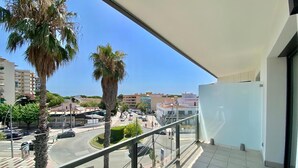 Un balcon offrant une vue dégagée sur une rue, des palmiers et des immeubles.