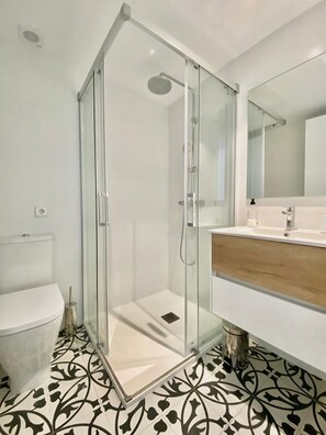 A modern bathroom with a glass-enclosed shower, a white toilet, and a wooden vanity with a sink. - Llevantí, near the sea (Platja D'Aro)