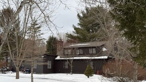 A two-story house with a snow-covered roof and a driveway leading to the front door.