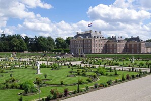 Un edificio grande e histórico con un jardín formal en su fachada.
