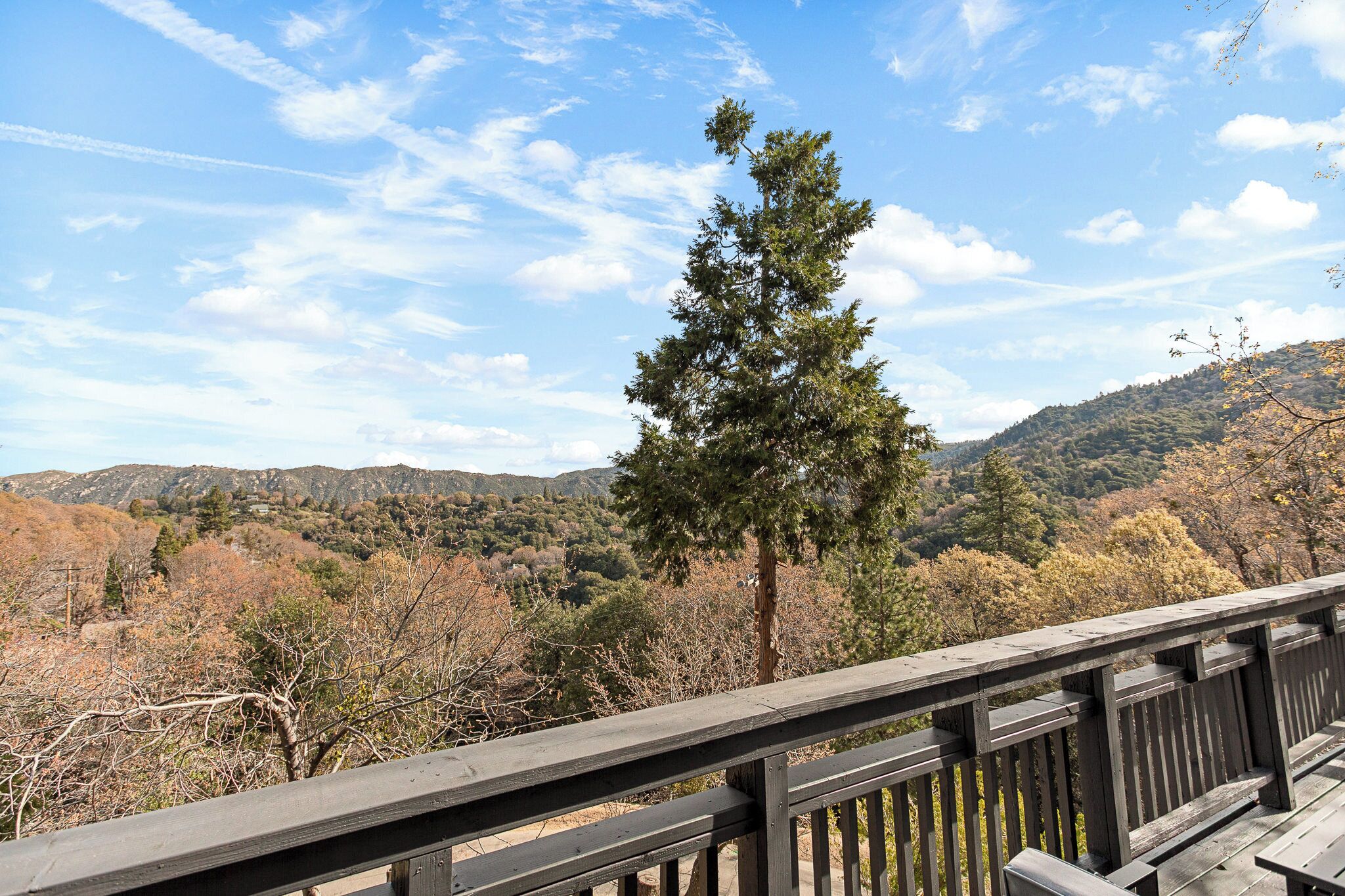 A wooden deck overlooking a mountainous landscape with autumn foliage.