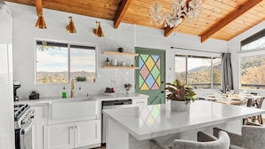 A modern kitchen with white cabinetry, a marble island, and a view of the outdoors.