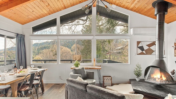 A cozy living room with a fireplace, large windows, and a dining area.