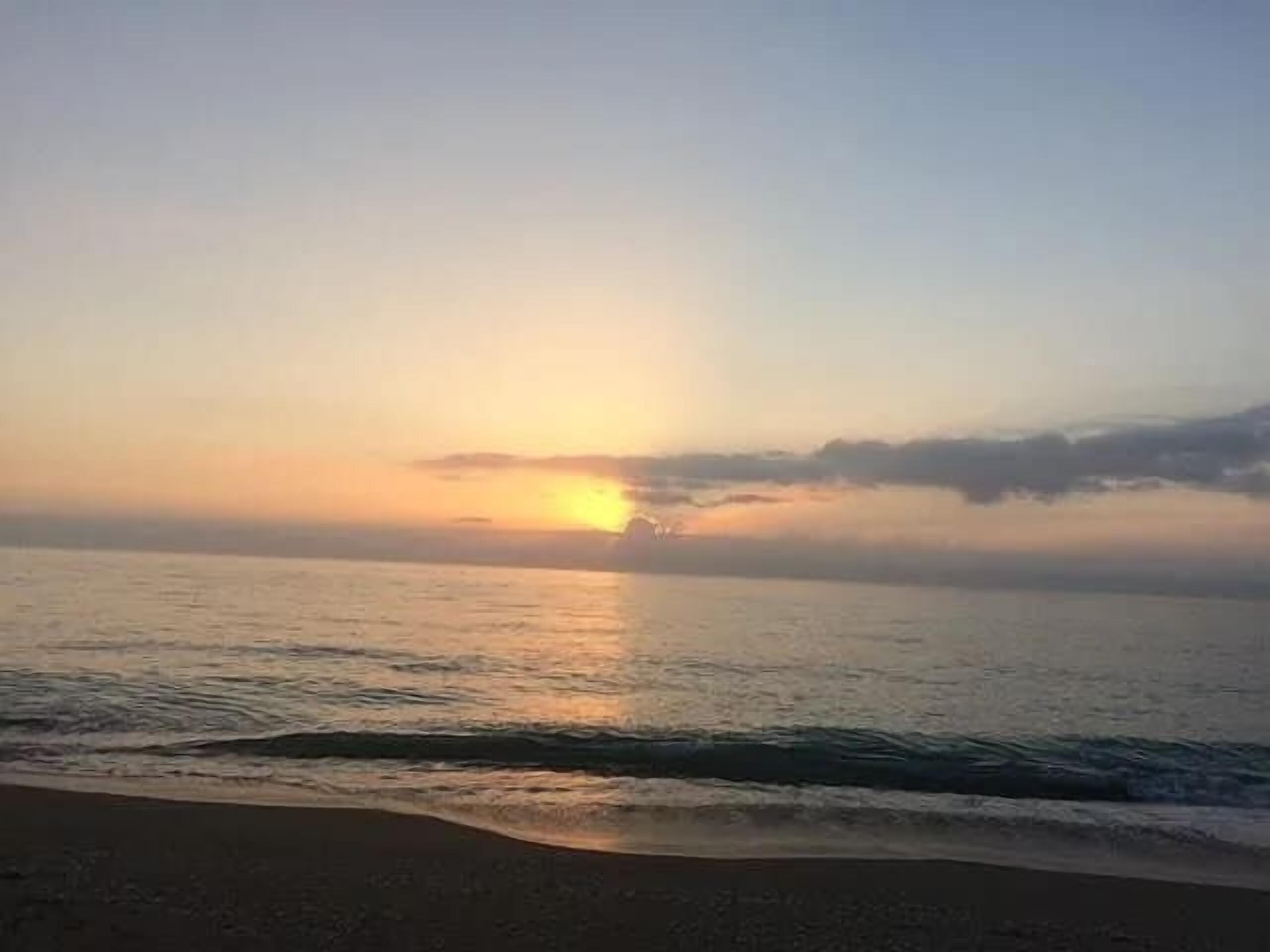 Uma praia com um pôr do sol sobre o oceano.