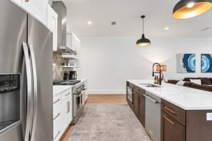 A modern kitchen with stainless steel appliances, a marble countertop, and a central island.