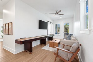 A modern living room with a pool table, a sofa, and a television mounted on the wall.