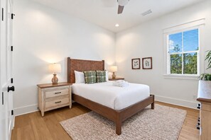 A bedroom with a wooden bed, bedside tables with lamps, a large window, and a view of trees. - Serenity at Treetop - 5BR/4.5BA Inlet Beach Home - Sleeps 10 - Golf Cart & Community Pool (Inlet Beach)