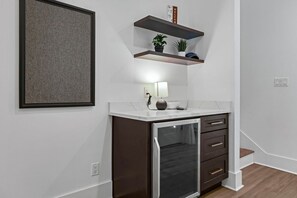 A modern kitchen with a built-in refrigerator, a countertop with a lamp, and a shelf with plants.