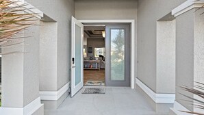 Un ingresso moderno con una porta in vetro che conduce a un soggiorno con divano e tavolino.