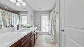 A bathroom with a white vanity, a toilet, and a shower area with patterned curtains.