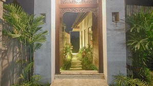 A well-lit entrance with a decorative archway leading to a pathway flanked by plants. - Umah Kemuning Near Central Ubud Bali (Bali)