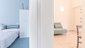 Ein Schlafzimmer mit Bett, Kleiderschrank und Blick auf eine Stadtlandschaft durch eine offene Tür.