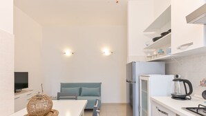 Eine moderne Küche mit weißer Arbeitsplatte, einem Einbauofen, einem Kühlschrank und einer Kaffeemaschine.