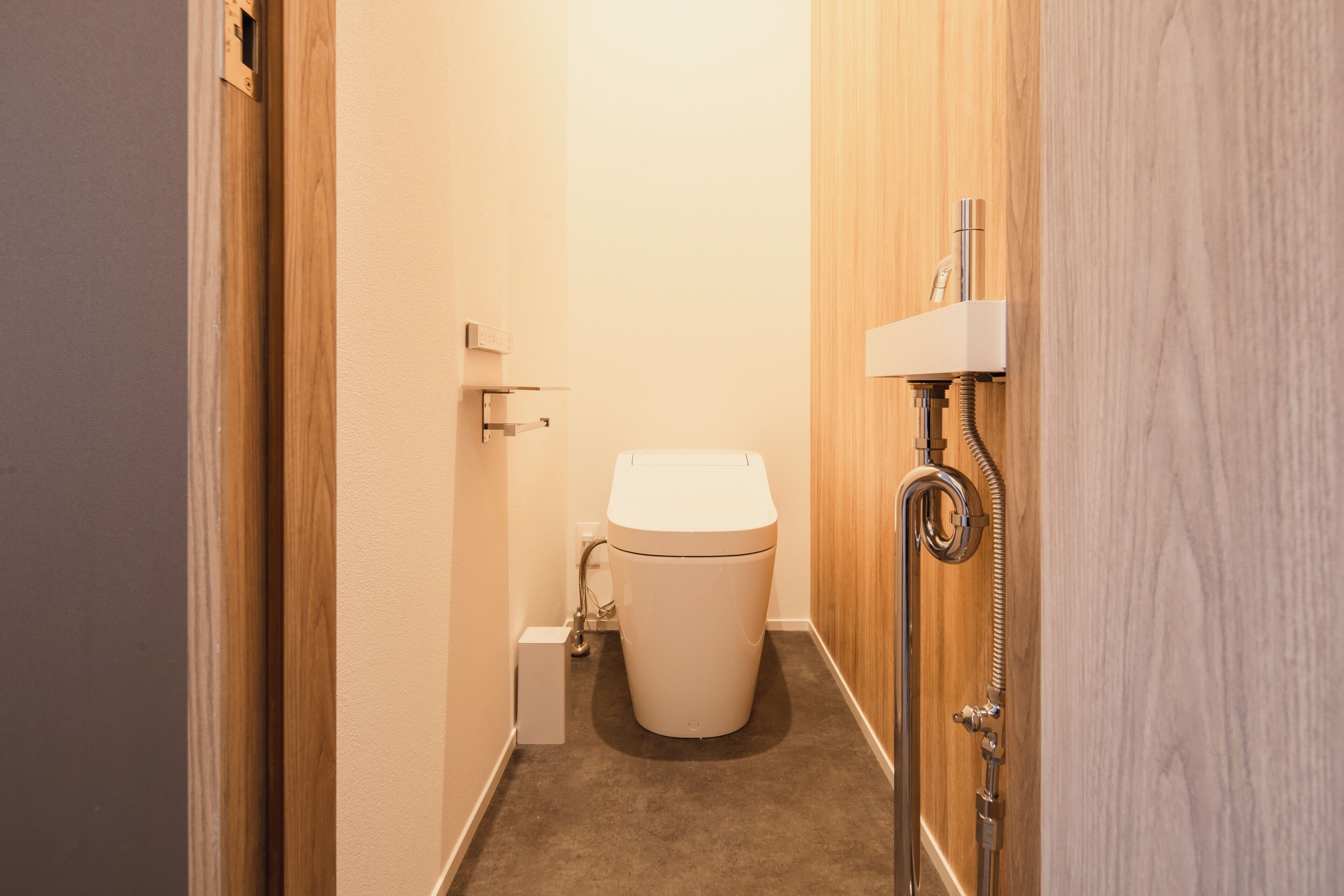 Un baño pequeño y estrecho con inodoro, ducha y puerta de madera.