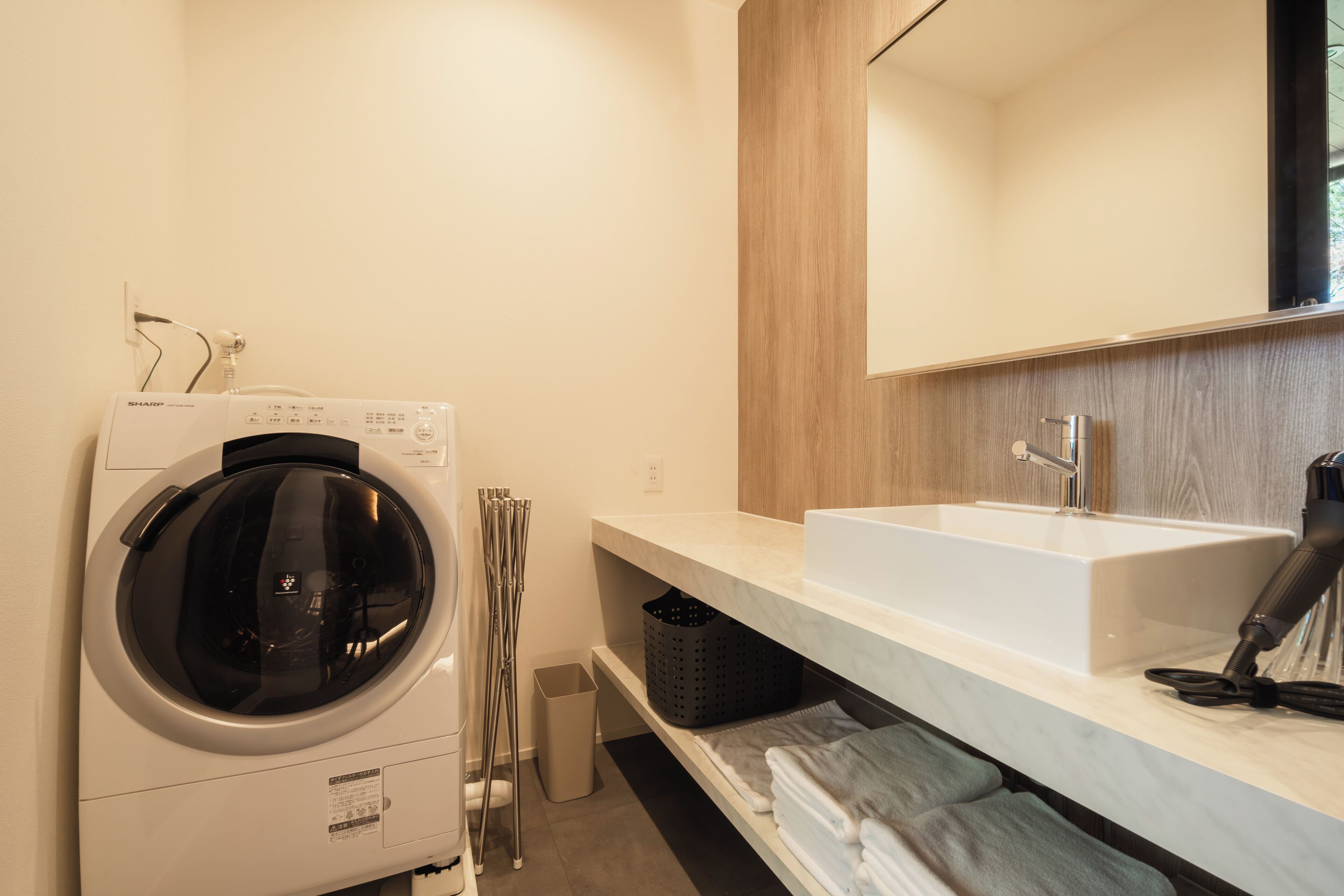 Un baño moderno con lavadora integrada, un lavamanos grande y un espejo.