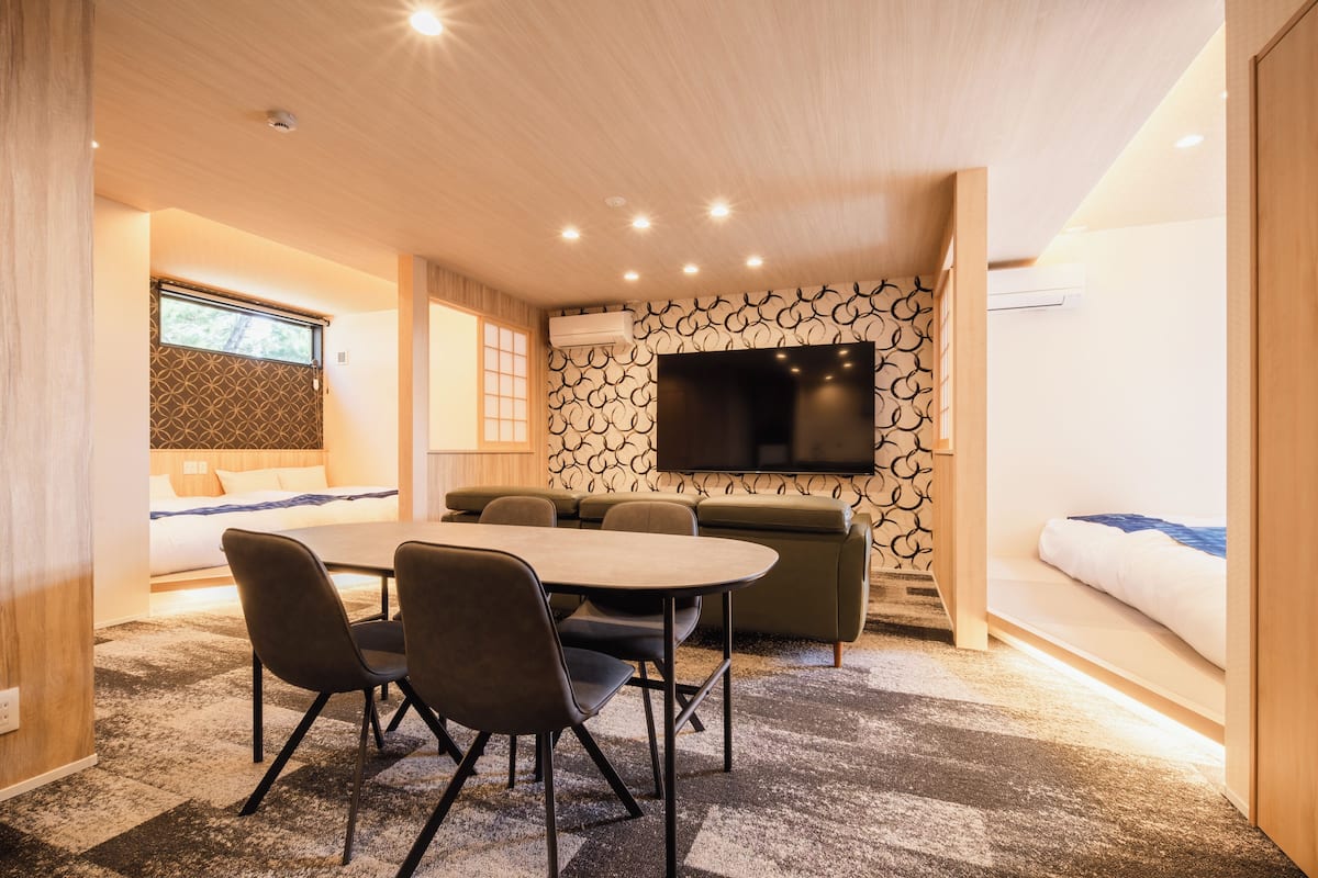 Een moderne hotelkamer met een zithoek, een bank, een flatscreen televisie aan de muur en een raam met uitzicht.