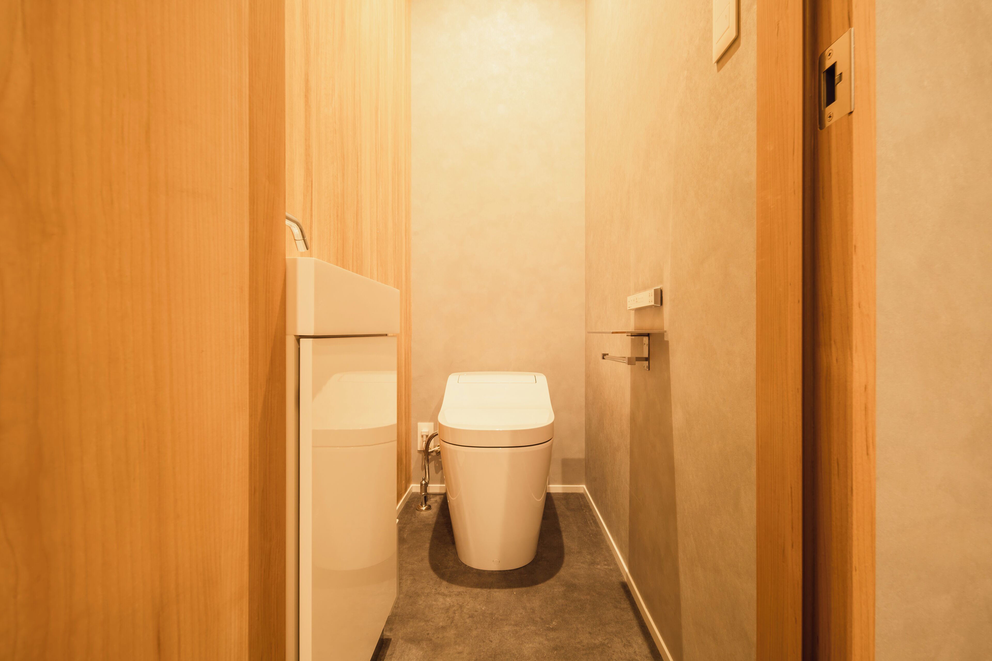 Un baño estrecho con inodoro, lavamanos y puerta de madera.