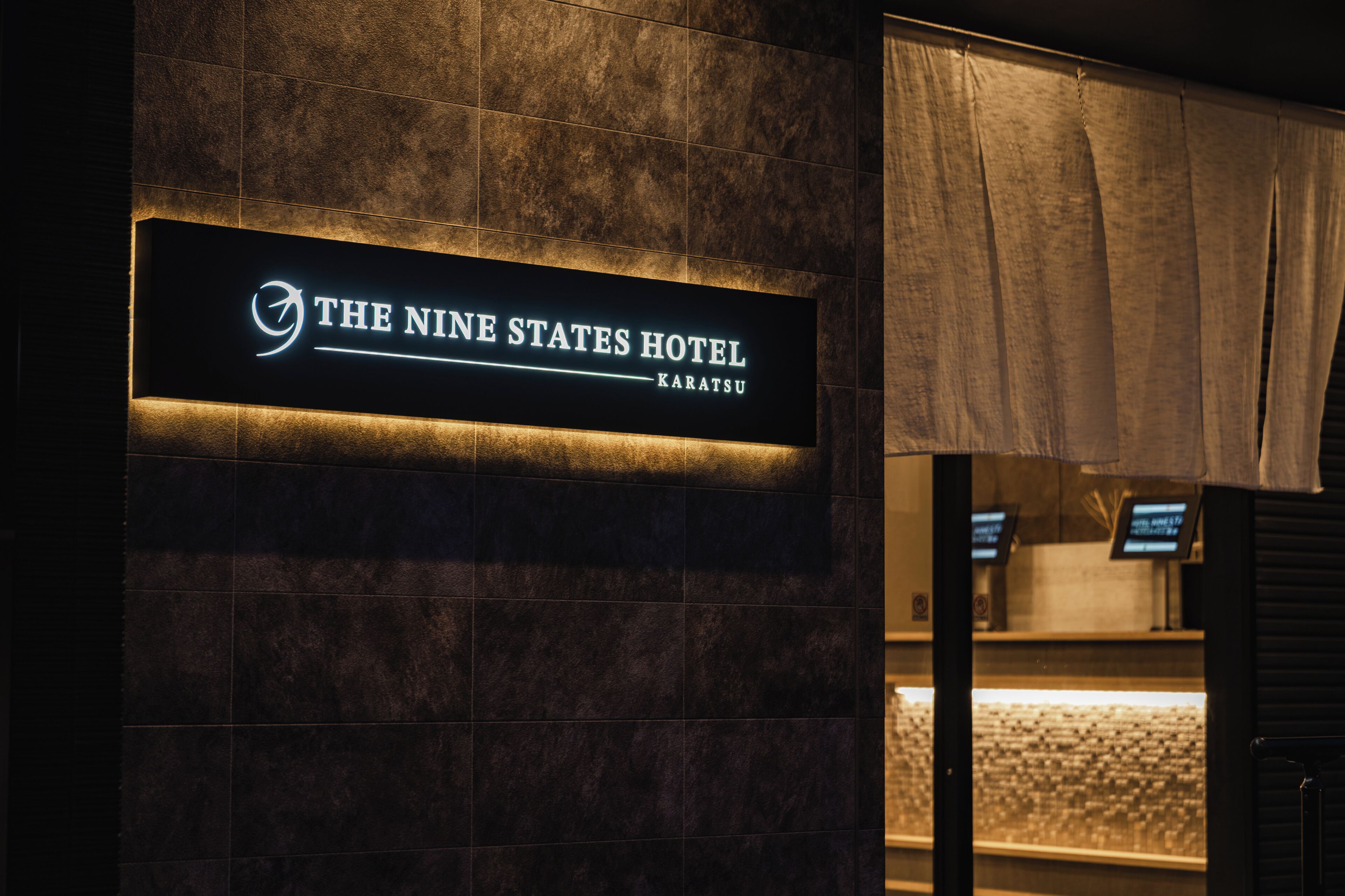 Ein Schild für das Hotel 'The Nine States Hotel' mit modernem Design und beleuchteter Schrift.
