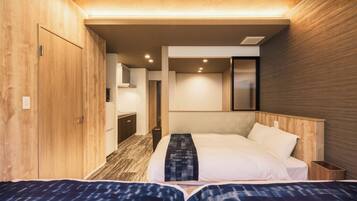 Quarto de hotel com duas camas, paredes de madeira, uma kitchenette pequena e um banheiro.