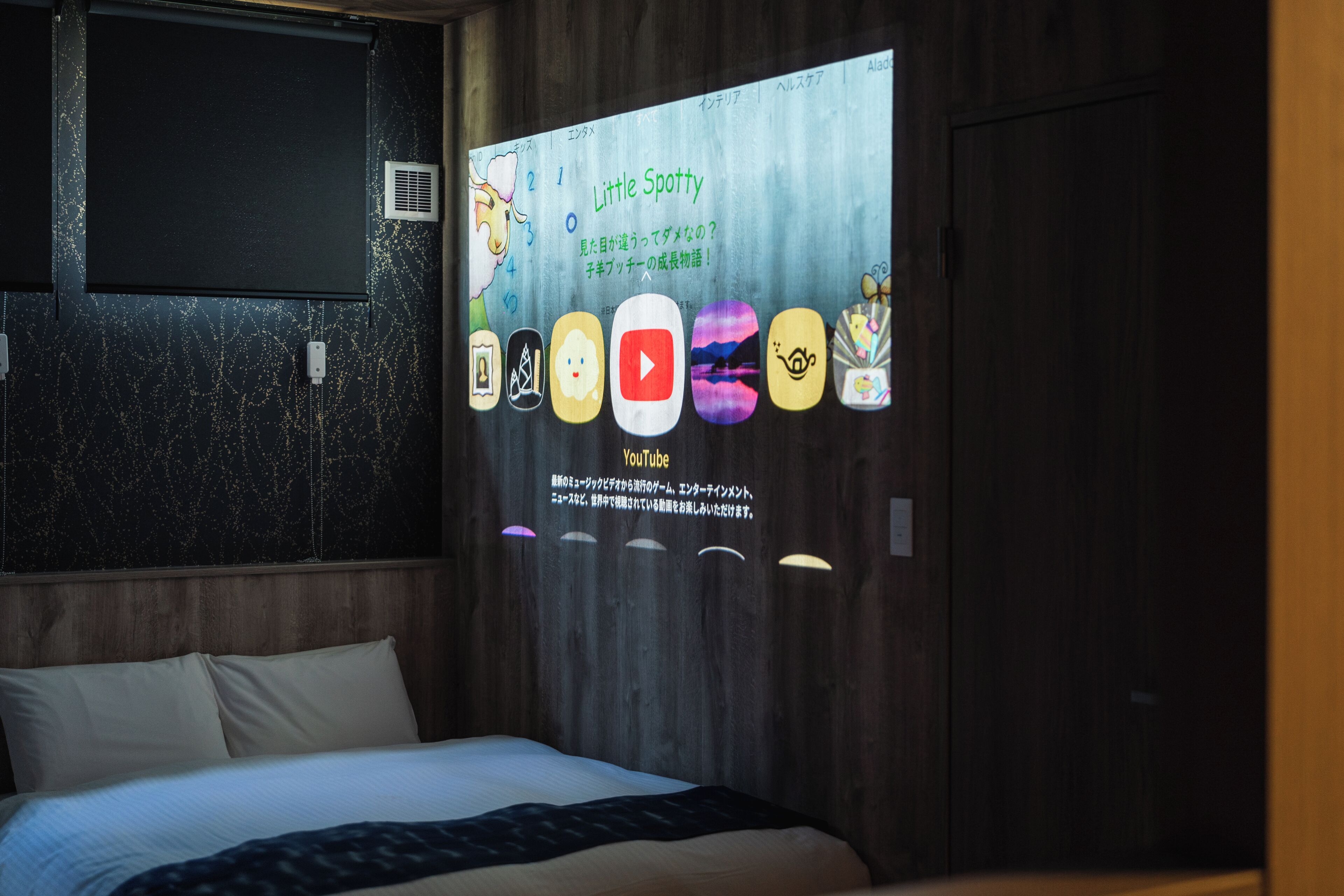 Habitación de hotel con cama, una pantalla mural que muestra un programa infantil y cabecero de madera.