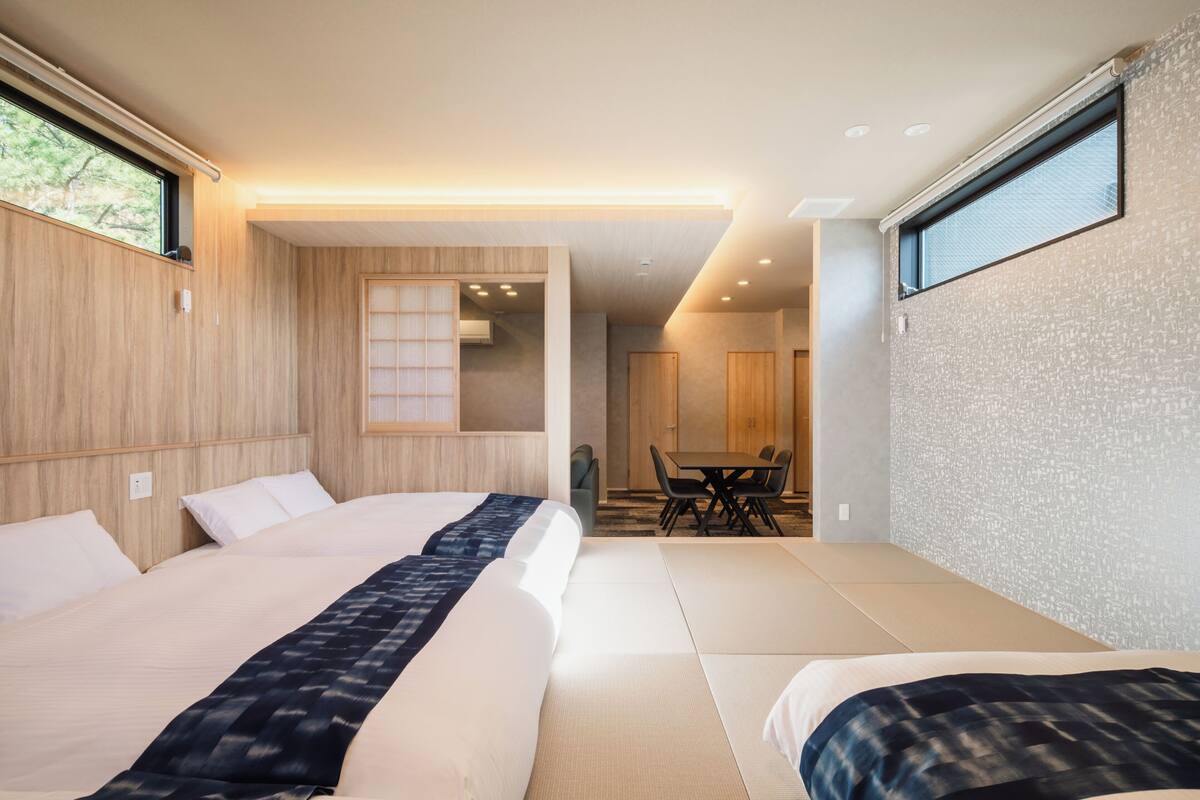 Een moderne hotelkamer met twee bedden, een zithoek en uitzicht op het omliggende landschap.