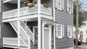 Una casa de dos pisos con balcón, puerta principal y escalera que conduce a la entrada.