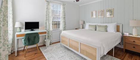 Un dormitorio con cama, escritorio, silla y ventilador de techo.