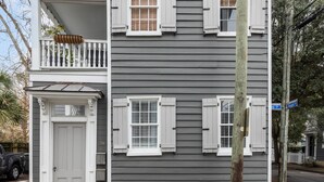 Una casa de dos pisos con un balcón, una puerta principal y una señal de calle que indica 'Boyer St'.
