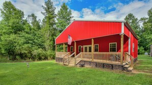 A red building with a wooden deck and a stone foundation.