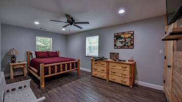 A bedroom with a wooden bed, a dresser, a nightstand, and a ceiling fan.