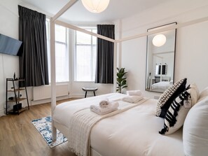 Relax in a serene space with a large bed, side table, and potted plant.