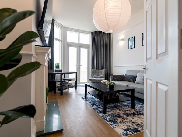 Relax in this stylish living room with a light grey sofa, dark grey armchair, and a coffee table, surrounded by a large window and a patterned rug.