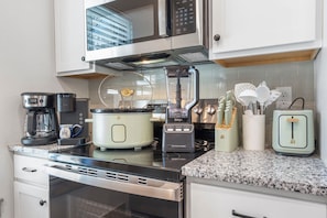 Eine moderne Küche mit Kaffeemaschine, Slow Cooker, Mixer, Toaster und Wasserkocher.