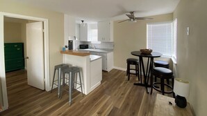 Une cuisine compacte dotée d’un îlot central, d’un coin repas avec des tabourets et d’un ventilateur de plafond.