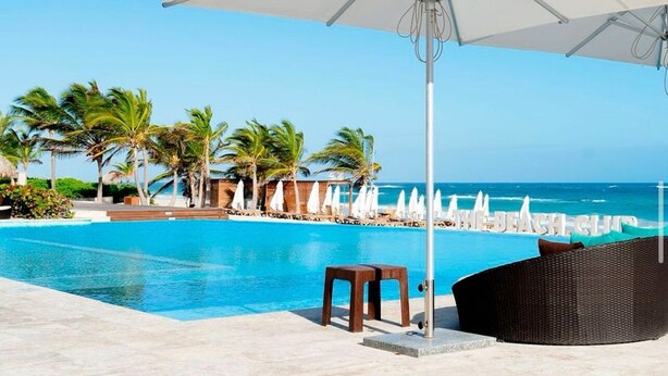Uma área na piscina com espreguiçadeira, mesa pequena e guarda-sol.