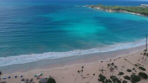 Uma praia com águas turquesa cristalinas, areal arenoso e palmeiras.