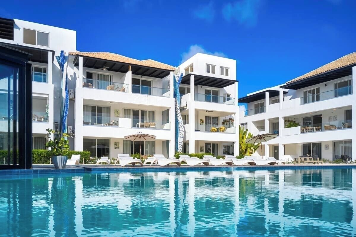 Ein modernes Hotel mit Pool, mehreren Balkonen und Sitzbereichen im Freien.