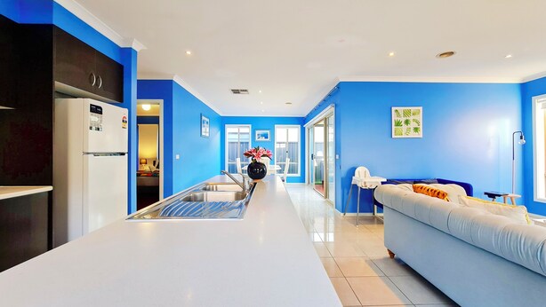 Una cocina moderna con una isla central, un área de comedor con una mesa y sillas, y una sala de estar con un sofá.